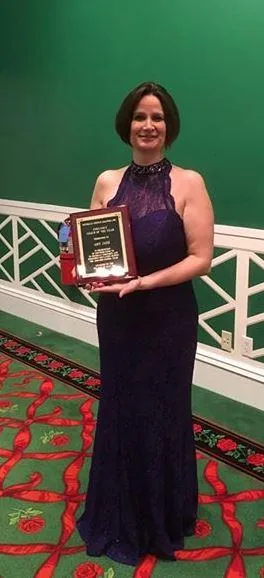 Amy Janz holding her Coach of the Year plaque at the Grand Hotel