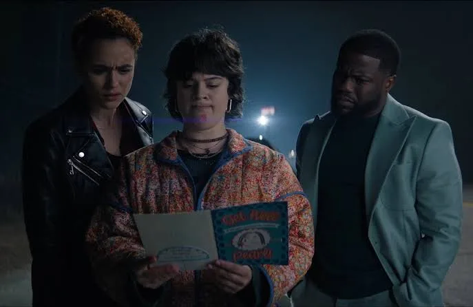 Nathalie Emmanuel, Anna Garcia and Kevin Hart read a greeting card outdoors at night