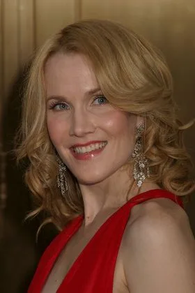 Erin Dilly smiles in a red dress and chandelier earrings against a warm gold background