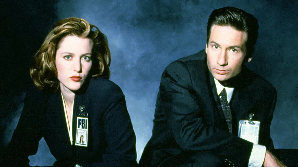 Gillian Anderson and David Duchovny in dark suits wearing FBI identification badges