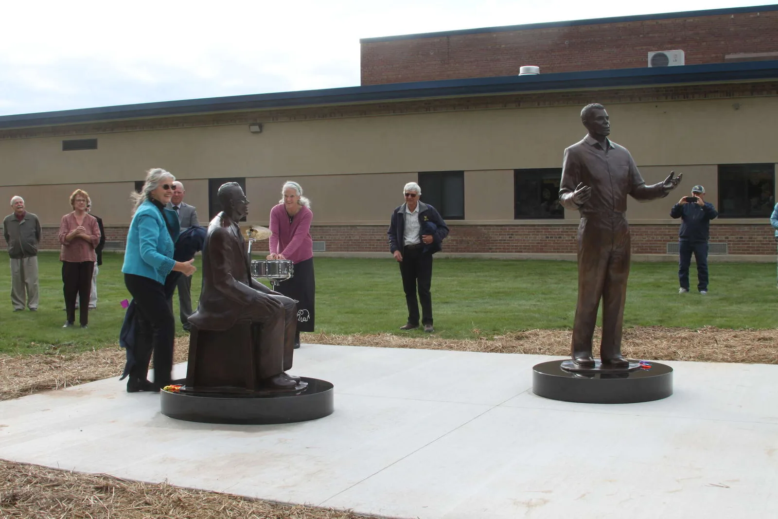 Two bronze statues outside a school: James Earl Jones standing with a raised hand, his teacher Donald Crouch seated, as onlookers watch