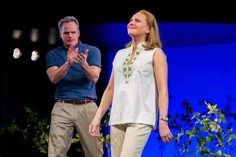 Jennifer Laura Thompson standing on stage in a white sleeveless top beside Norbert Leo Butz applauding