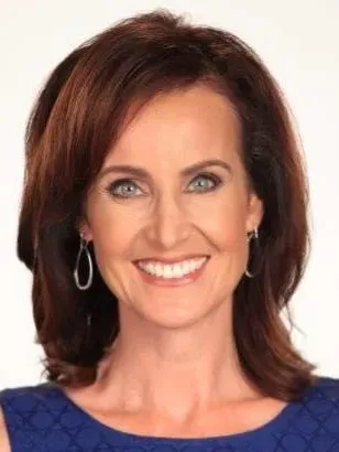 Close headshot of JoAnne Purtan smiling in a blue top against a white background