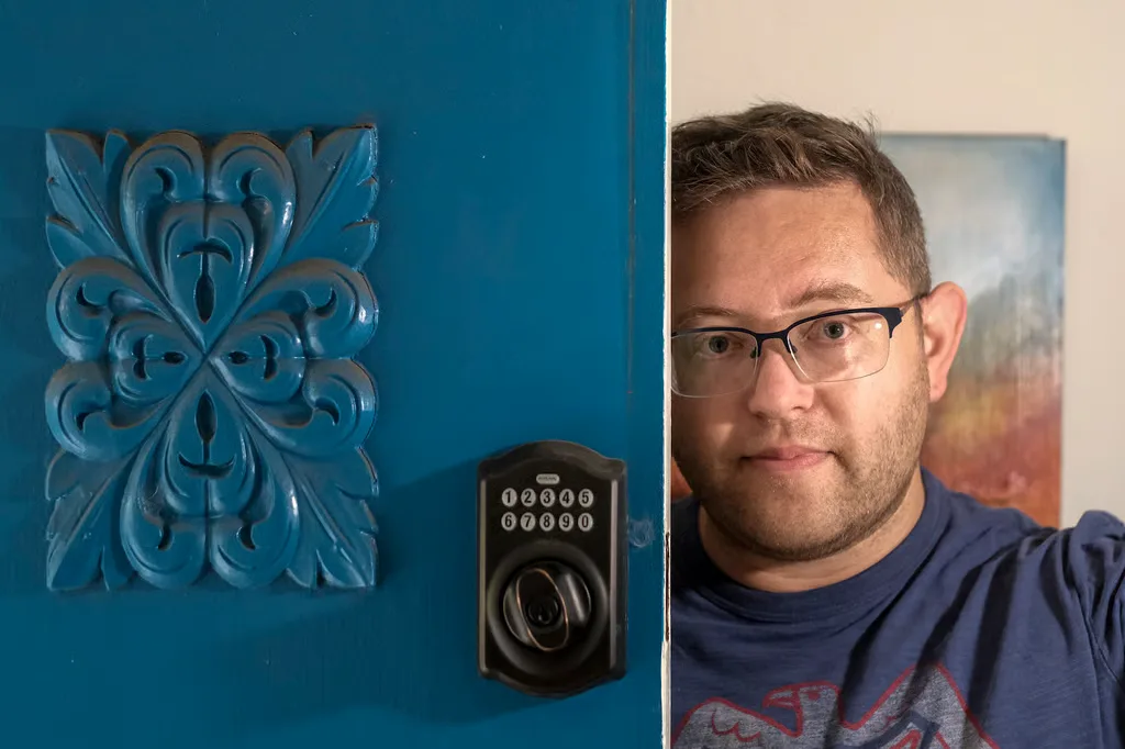 Joshua Steinman looking out from behind a carved teal door fitted with a keypad deadbolt