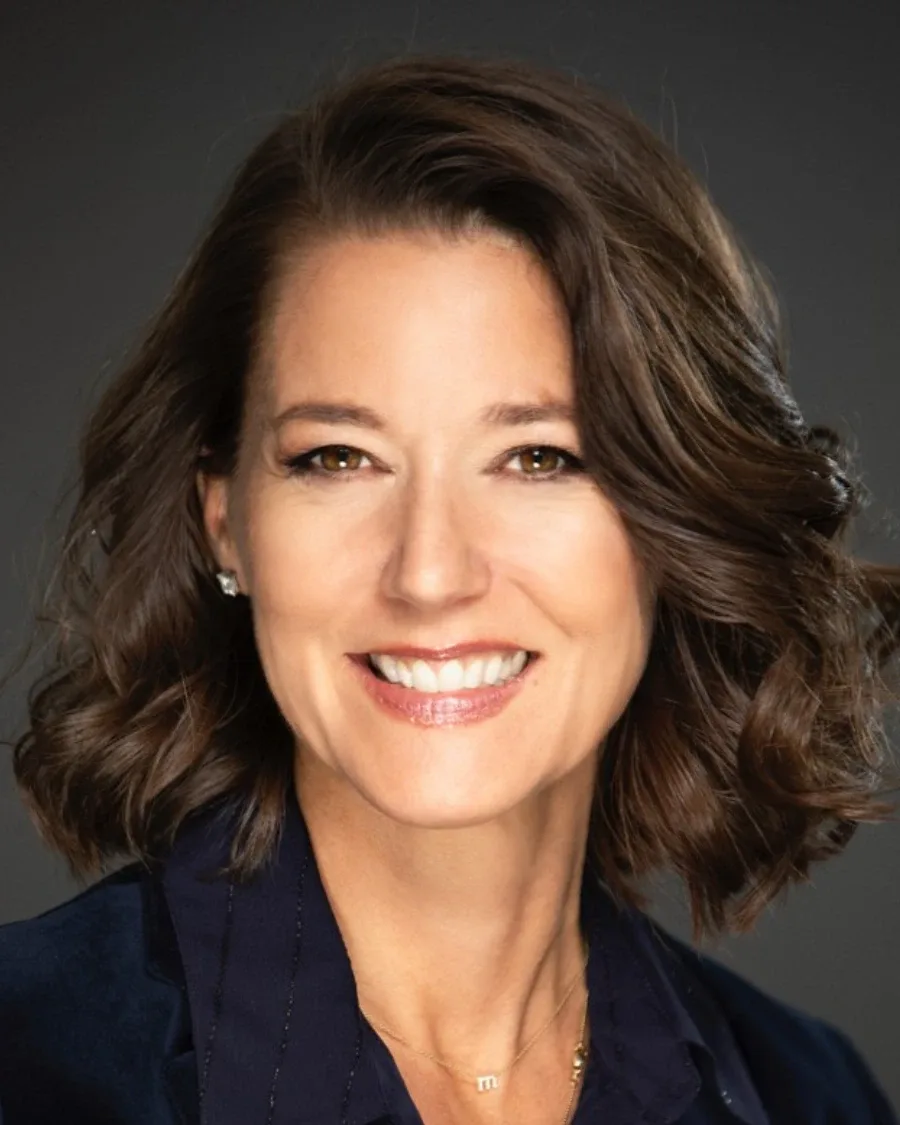 Mary Ellen Coe smiling in a portrait, wearing a navy jacket