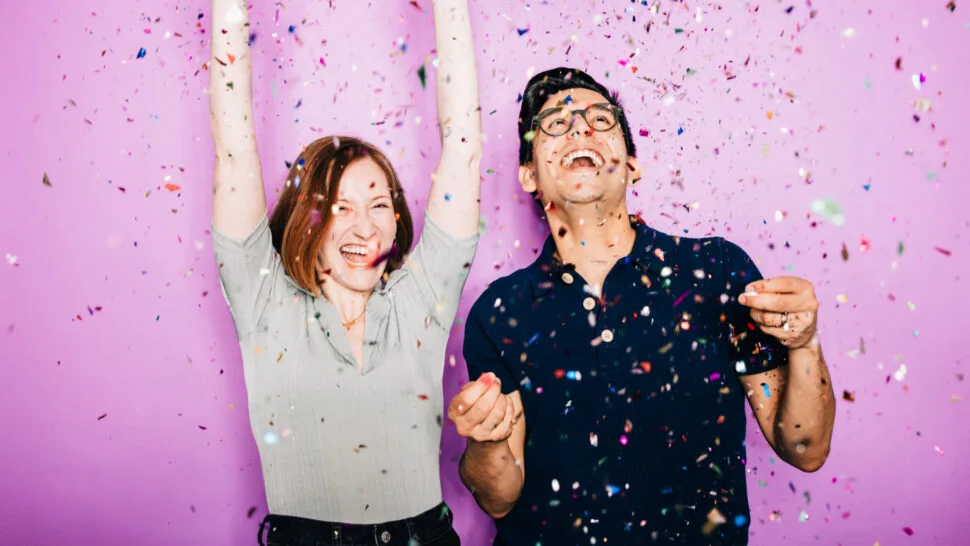Rachel Sussman and Sammy Lopez raise their arms and laugh as confetti falls around them