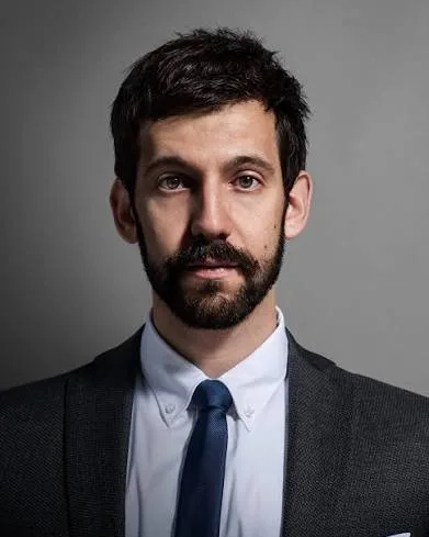 Rob Cantor in a dark suit and navy tie looks directly at the camera