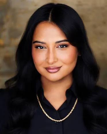 Sowmya Krishnamurthy in a black collared shirt and gold chain necklace