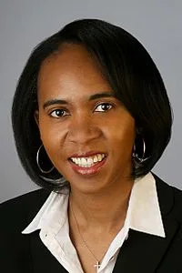 Judge Tiffany P. Cunningham in a black blazer with hoop earrings, against a grey studio background