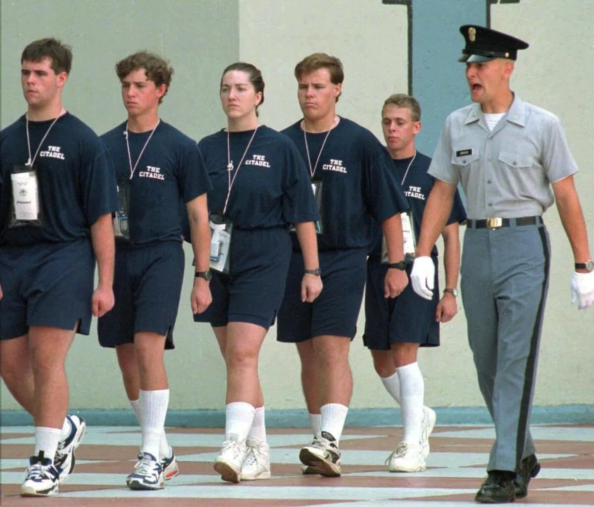 Shannon Faulkner, center, in a Citadel T-shirt and shorts, marching with male recruits while a uniformed cadet calls out beside the line
