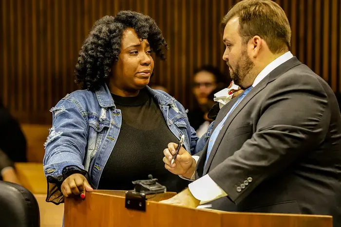 Wade Fink in a suit speaking with his client across a courtroom lectern